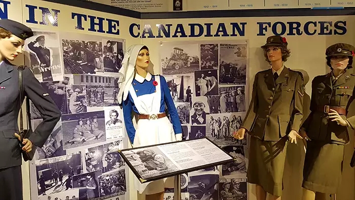Models of four women including an early blue and white nurse's uniform and three military uniforms. 