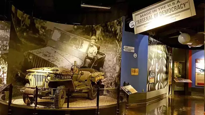 Jeep display with historic photo on the wall and signage that reads: MADE IN THE U.S.A. Arsenal of Democracy. 