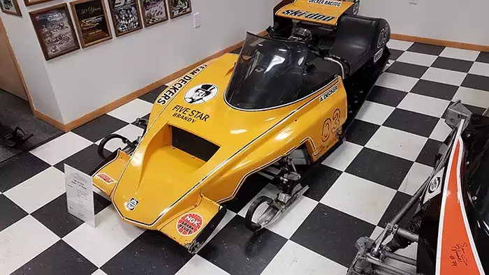Yellow Team Deckers race sled on a black-white checkered floor. 