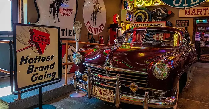 Maroon colored vintage car with a Conoco sign. 